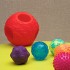 Z dużej piłki można wyjmować małe piłeczki, ćwicząc koordynację. Każda z piłeczek jest inna (inne wykonanie, inaczej zachowuje się w rękach dziecka). Piłeczki można umieszczać w otworach dużej piłki, a można je turlać, rzucać nimi do pudełka. Dziecko może je również wąchać, wkładać do buzi.     