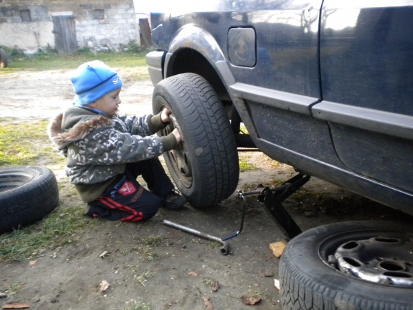 Mój duży synuś &#45; pomocnik. Ksawek pomaga zmienić koła w samochodzie. Jeszcze trochę i sam to zrobi.