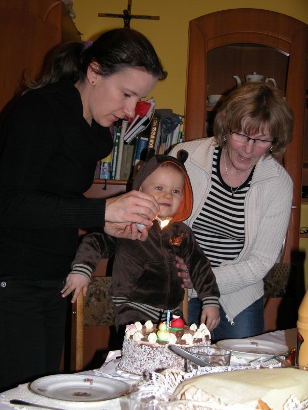 ROCZEK FRANKA JANKA Mama Ania zapala świeczkę, a babcia Terenia trzyma solenizanta żeby nie zatopił swojej ciekawskiej rączki w torcie.\nDużo zdrowia Franiu.\nMama