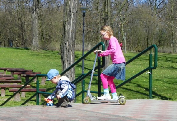 w parku Każdy robi to co lubi : córka ćwiczy na hulajnodze, a synek robi garaż dla autka!