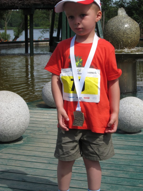 Mały biegacz Tomek z pierwszym swoim medalem zdobytym w czasie minionych wakacji. Bieg na 200 metrów; Gołdap; zawody Garmin Triathlon