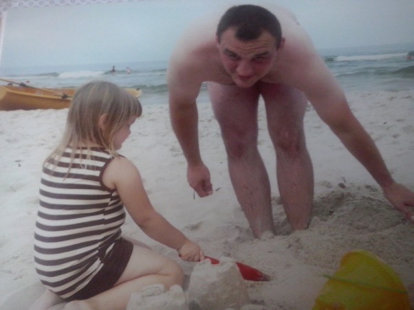 zabawa w goracym piasku Tata bawi się z córką w piasku,stawia babki z piasku,smieja się i ciesza.